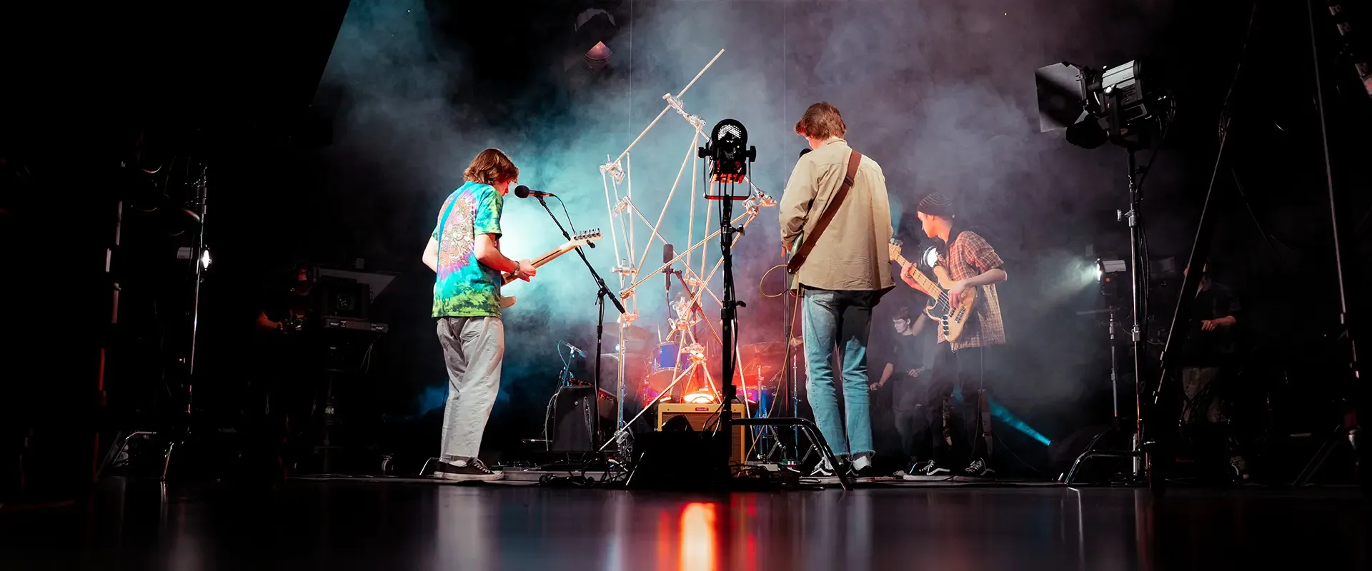 people standing in smoke machine, playing guitars